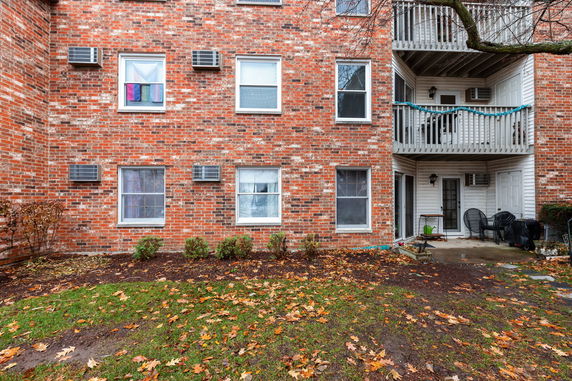 Front view of a multi-story brick apartment building with balconies and window air conditioning units.