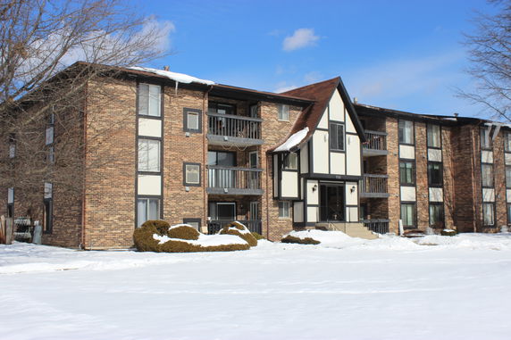 Front view of a multi-story building with brick facade and balconies.