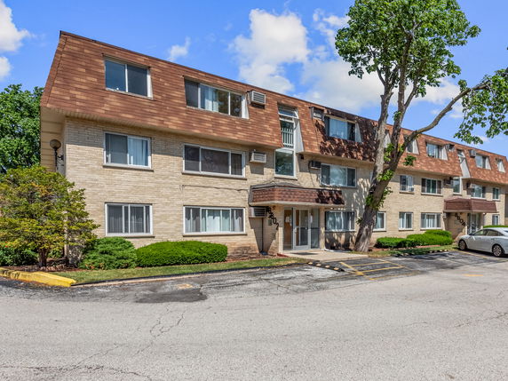 Front view of a three-story apartment building with a sloped roof.