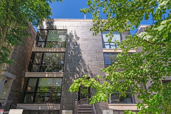 Front view of a modern multi-story building with large windows and a brick exterior.