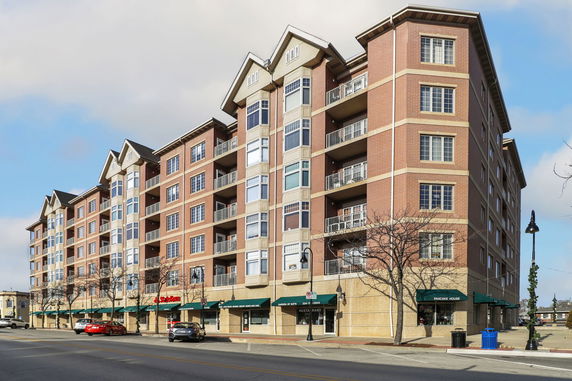 Front view of a multi-story building with exterior balconies and retail shops on the ground floor.