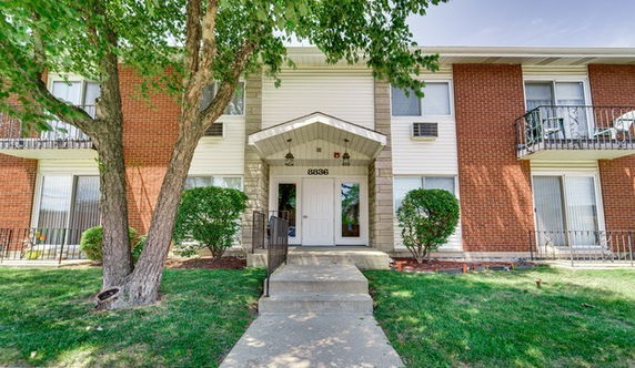 Front view of a two-story apartment building with brick facade and entrance steps.