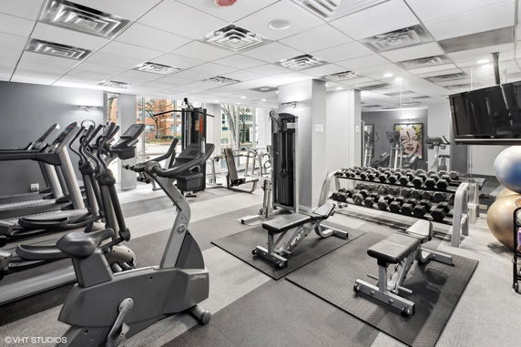 Indoor gym area with various exercise equipment and weights.