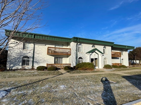 Front view of a two-story apartment building with balconies and green roof.