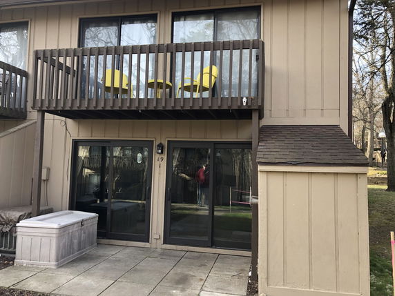 Back view of a two-story house with balcony and sliding glass doors.
