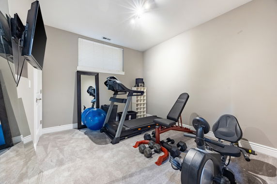 Home gym with exercise equipment including a treadmill, weights, and exercise ball.