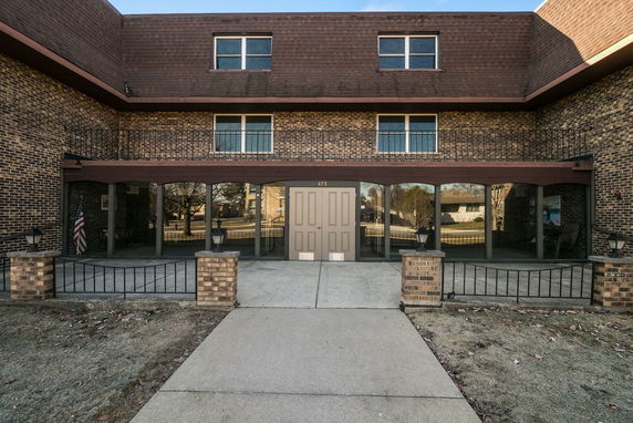 Front view of a two-story brick building with a balcony and large windows.