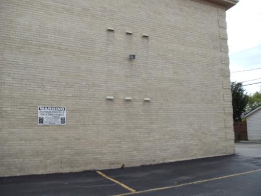Side view of a building with a plain brick wall and small light fixture.