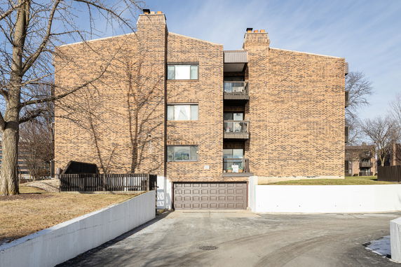 Front view of a multi-story brick building with balconies and a garage entrance.