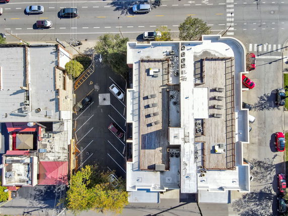 Aerial view of a building with a rooftop featuring air conditioning units and seating area.