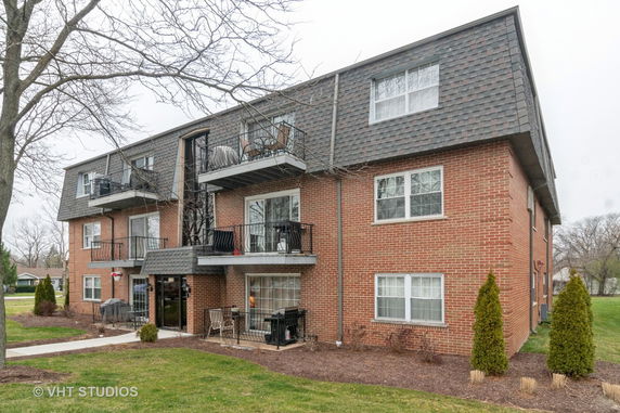 Front view of a multi-story brick apartment building with balconies.
