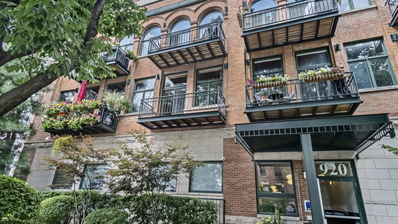 Front view of a multi-story building with balconies adorned with plants.