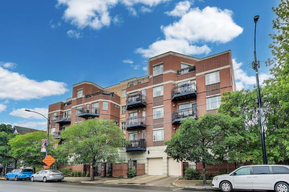 Front view of a multi-story brick apartment building with balconies.