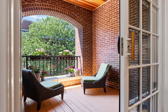 View from a covered balcony with brick walls and outdoor seating.
