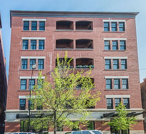 Front view of a multi-story brick building with large windows.