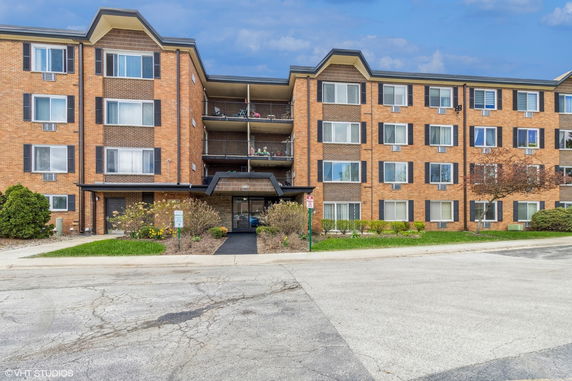 Front view of a multi-story brick apartment building with balconies.