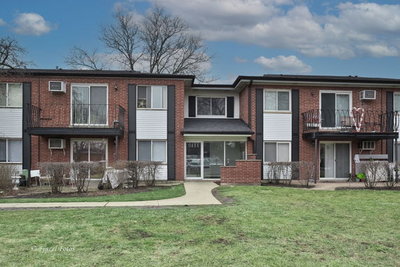Front view of a two-story brick apartment building with balconies.