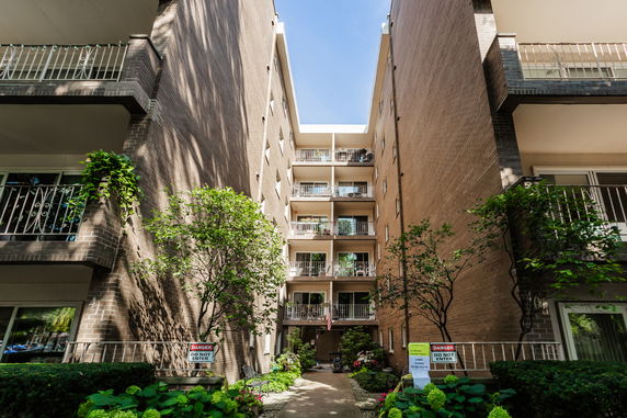 Front view of a multi-story building with balconies and brick exterior.