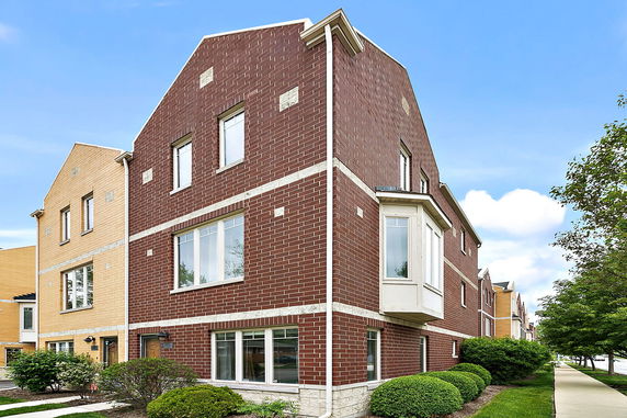 Front view of a multi-story brick house with large windows.