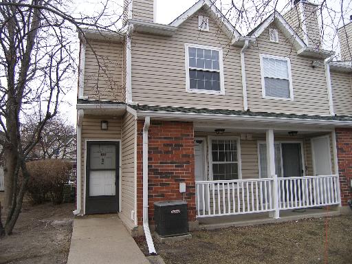 Front view of a two-story townhouse with a porch and white railing.