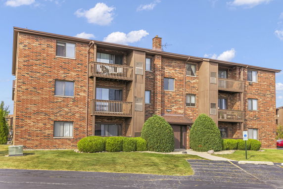 Front view of a multi-story brick apartment building with balconies.