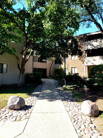 Front view of a multi-story residential building with a walkway leading to the entrance.