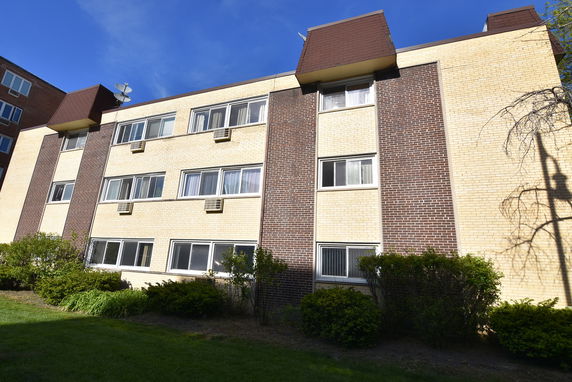 Front view of a three-story apartment building with a brick facade.