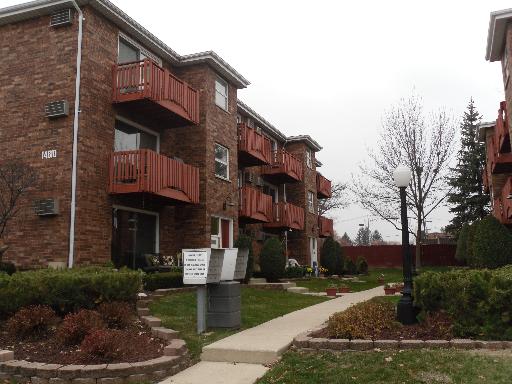 Front view of a multi-story brick apartment building with balconies.