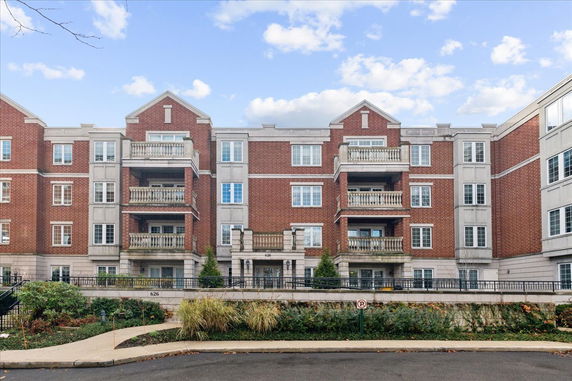 Front view of a multi-story building with red brick facade and numerous balconies.