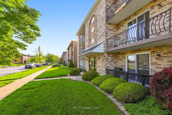 Front view of a multi-story apartment building with balconies and brick exterior.