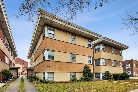 Front view of a multi-story brick apartment building with flat roof.
