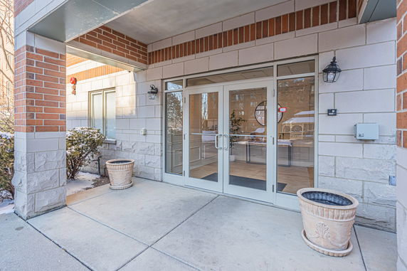 Front view of a building entrance with glass doors and two planters.