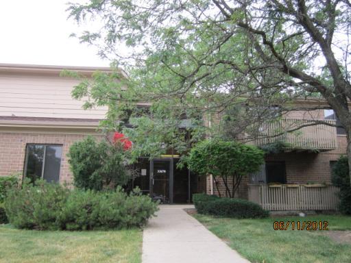 Front view of a two-story residential building with a brick facade and a balcony.