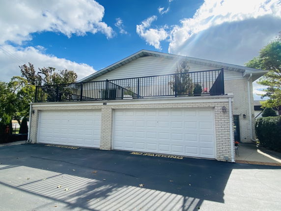 Front view of a two-story house with a three-car garage and a balcony on top.