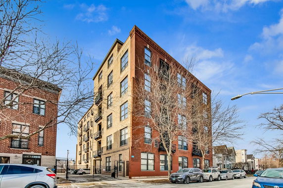 Front view of a multi-story brick apartment building with large windows.