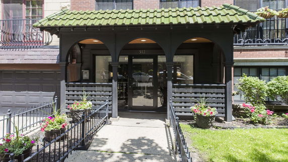 Front view of a building entrance with green tiled canopy and decorative metal railings.