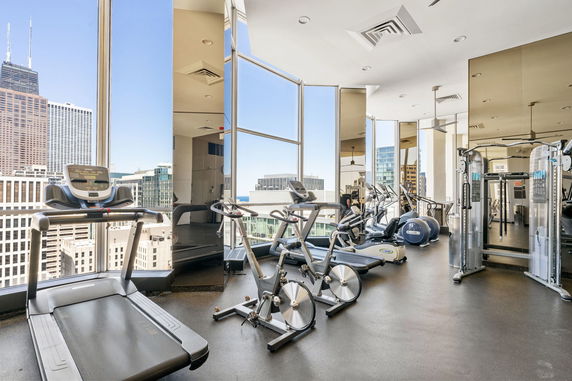 Interior view of a gym with exercise equipment and large windows.