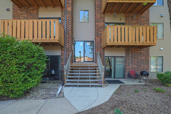 Front view of a multi-story apartment building with balconies and a central staircase.