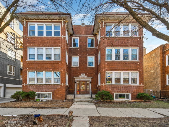 Front view of a brick apartment building with multiple windows and a central entrance.