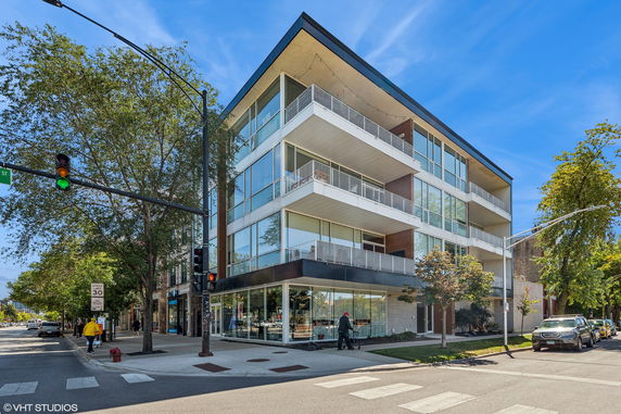 Front view of a modern multi-story building with balconies and large windows.