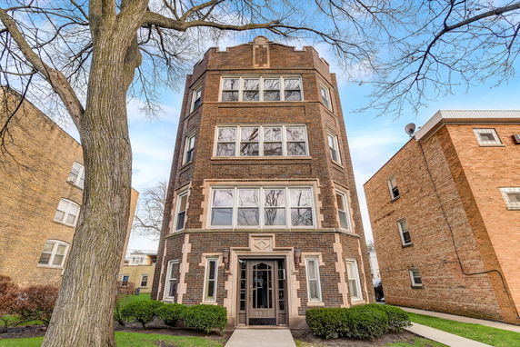 Front view of a four-story brick building with large windows.