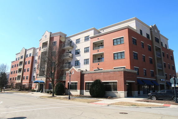 Front view of a multi-story brick apartment building with balconies.