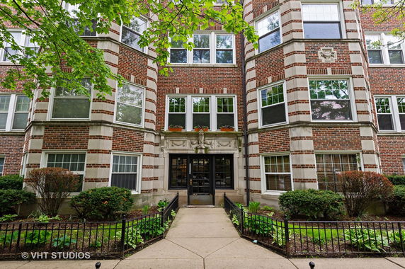 Front view of a multi-story brick building with large windows and an entrance pathway.