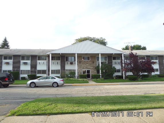 Front view of a multi-story residential building with a central entrance and balconies.