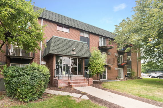 Front view of a three-story brick apartment building with balconies.