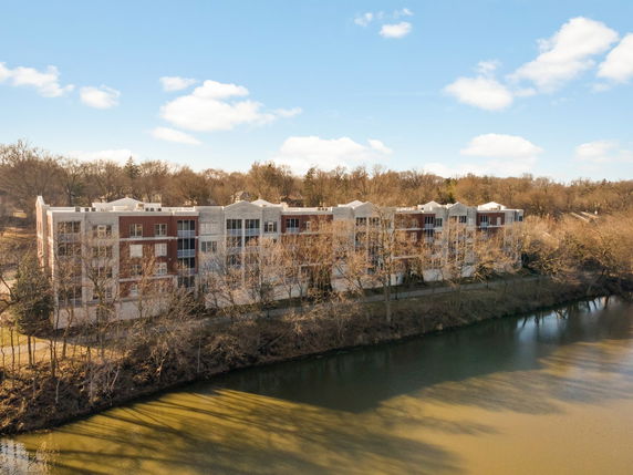 Front view of a multi-story apartment building near a body of water.