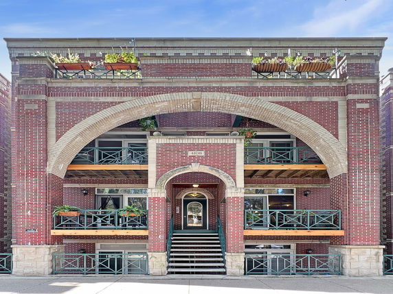 Front view of a multi-story building with brick facade and balconies.