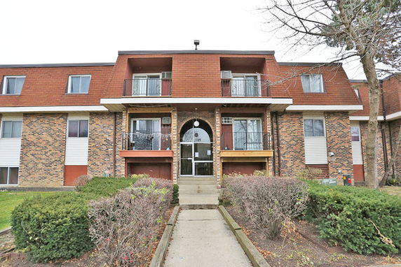 Front view of a multi-story apartment building with a central entrance and balconies.
