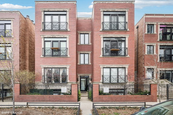 Front view of a three-story brick building with balconies.