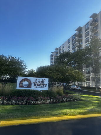 Front view of a multi-story condominium building with a sign reading 'Golf Towers Condominium'.